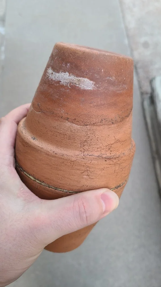 Picture of a dirty stained olla with mineral deposits toward the top.